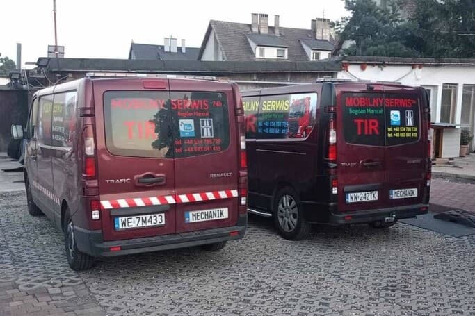 Dwa samochody stojące obok siebie. Na boku i tyle mają napisy reklamowe - serwis mobilny tir.