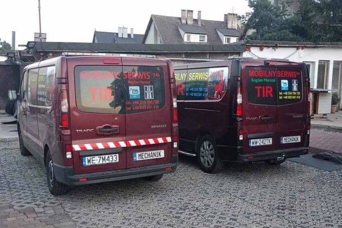 Dwa samochody stojące obok siebie. Na boku i tyle mają napisy reklamowe - serwis mobilny tir